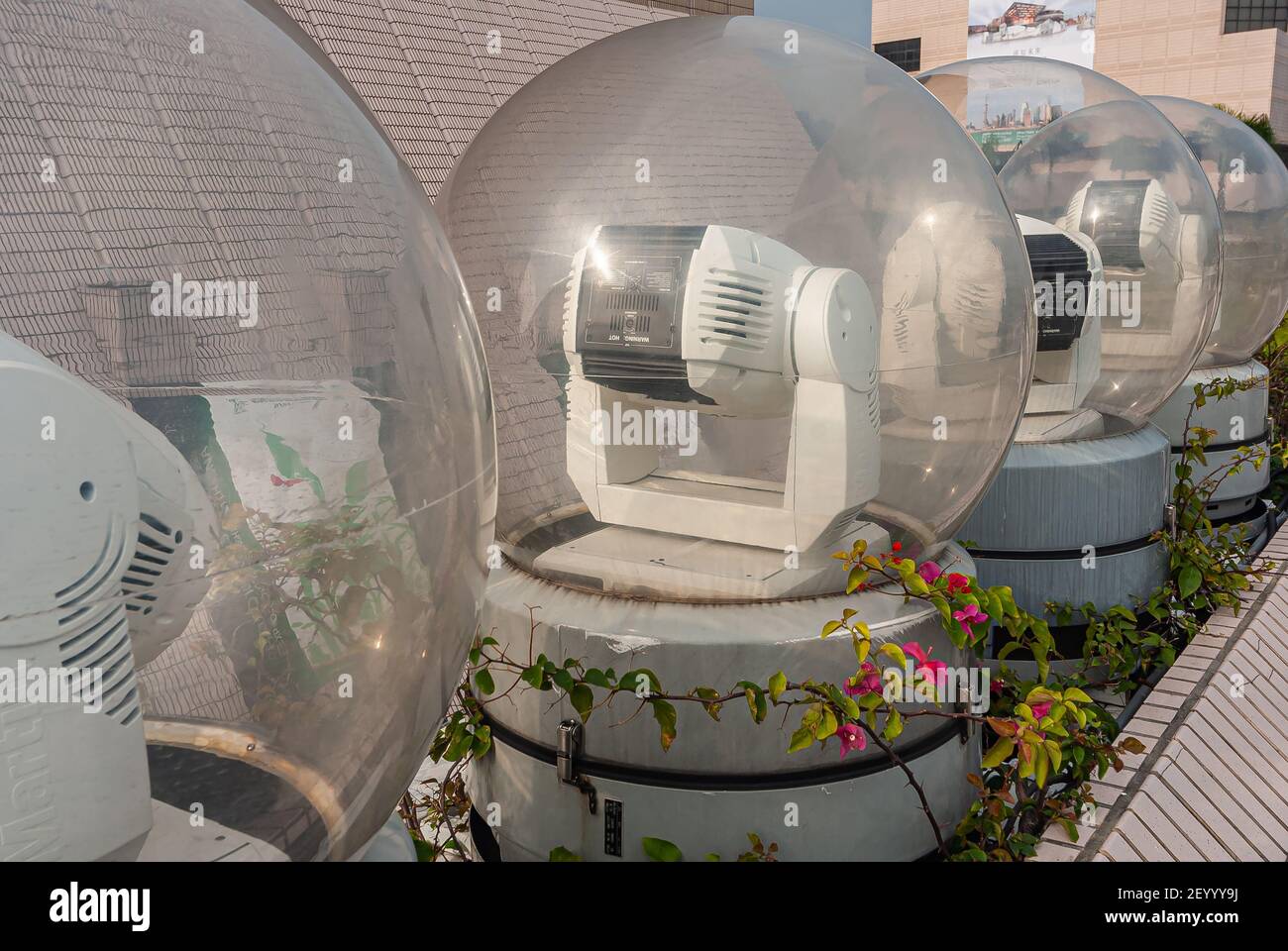Kowloon, Hong Kong, China - May 13, 2010: Line of white robotic light canons under glass sphere to work during evening light show. Stock Photo