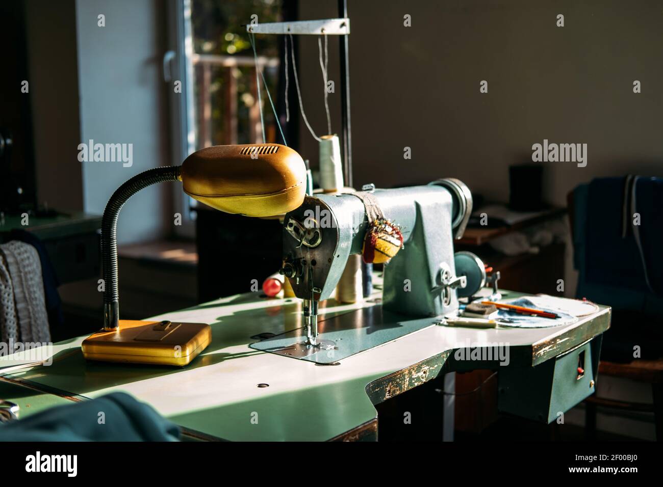 Sewing machine on table in factory in sun light. Small business, fashion designe, Tailor working, candid dressmaker workplace, Clothing or garment Stock Photo