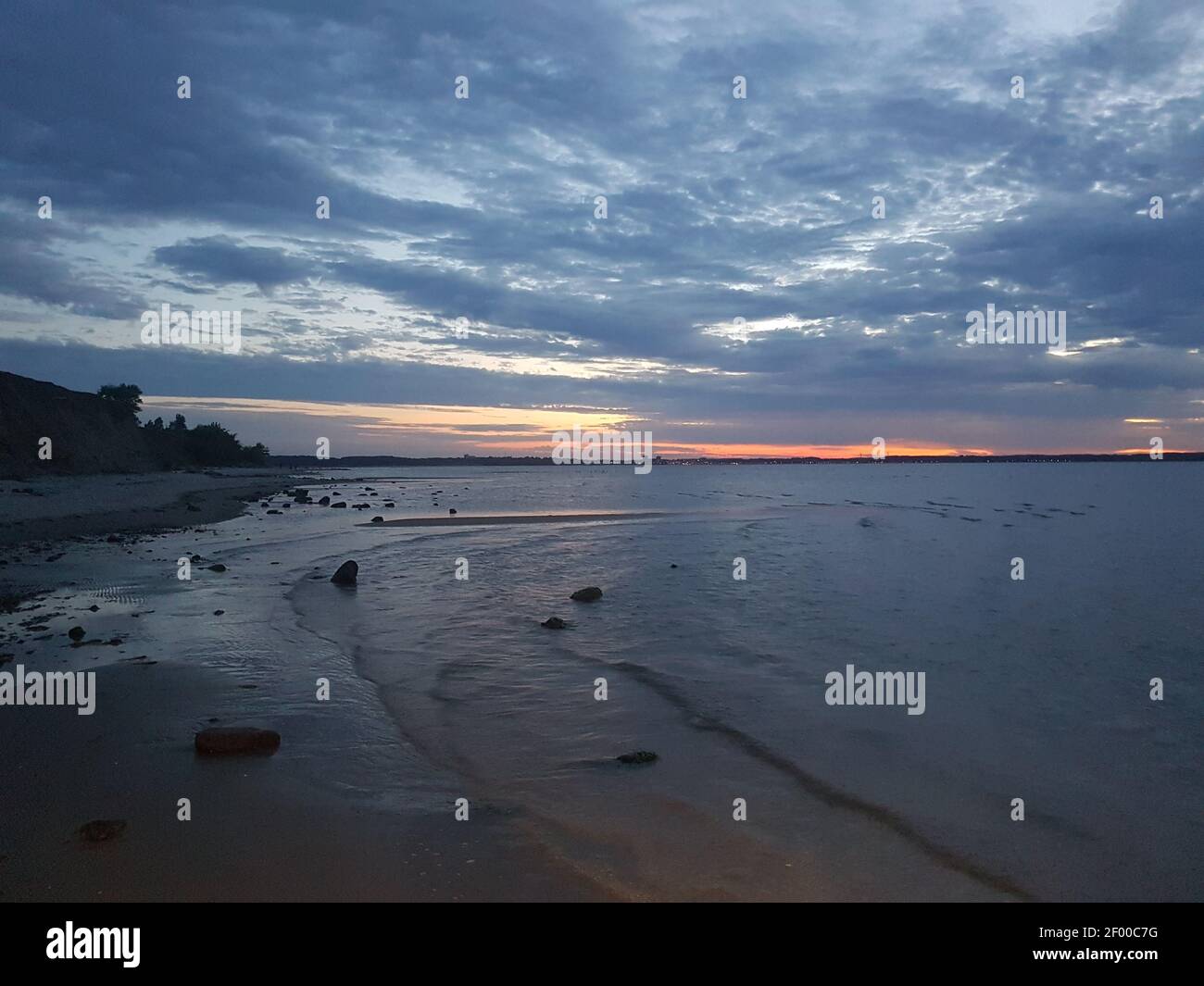 The sandy beach under the cloudy sky during sunset Stock Photo - Alamy