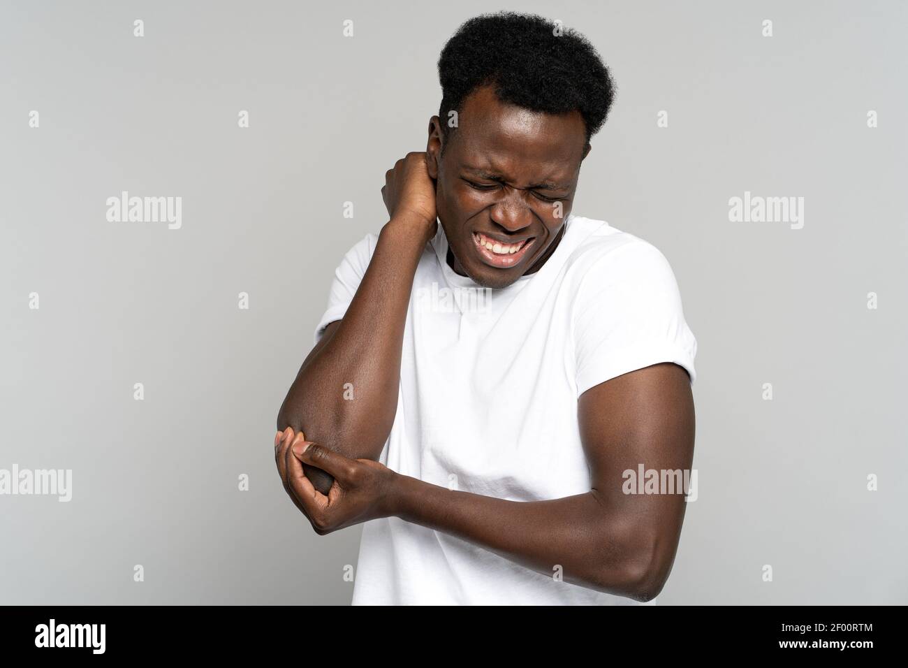 Unhappy Black man in tshirt suffers her elbow joint pain or arm bone