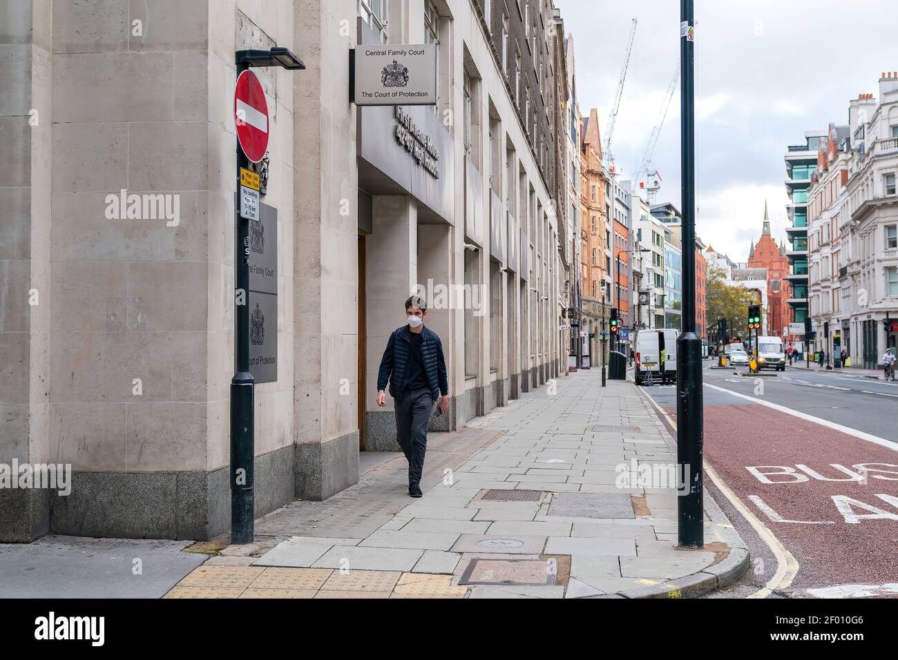 LONDON, ENGLAND - OCTOBER 23, 2020:  Man wearing a face mask walking outside the Central Family Court, Principal Registry of the Family Division of th Stock Photo