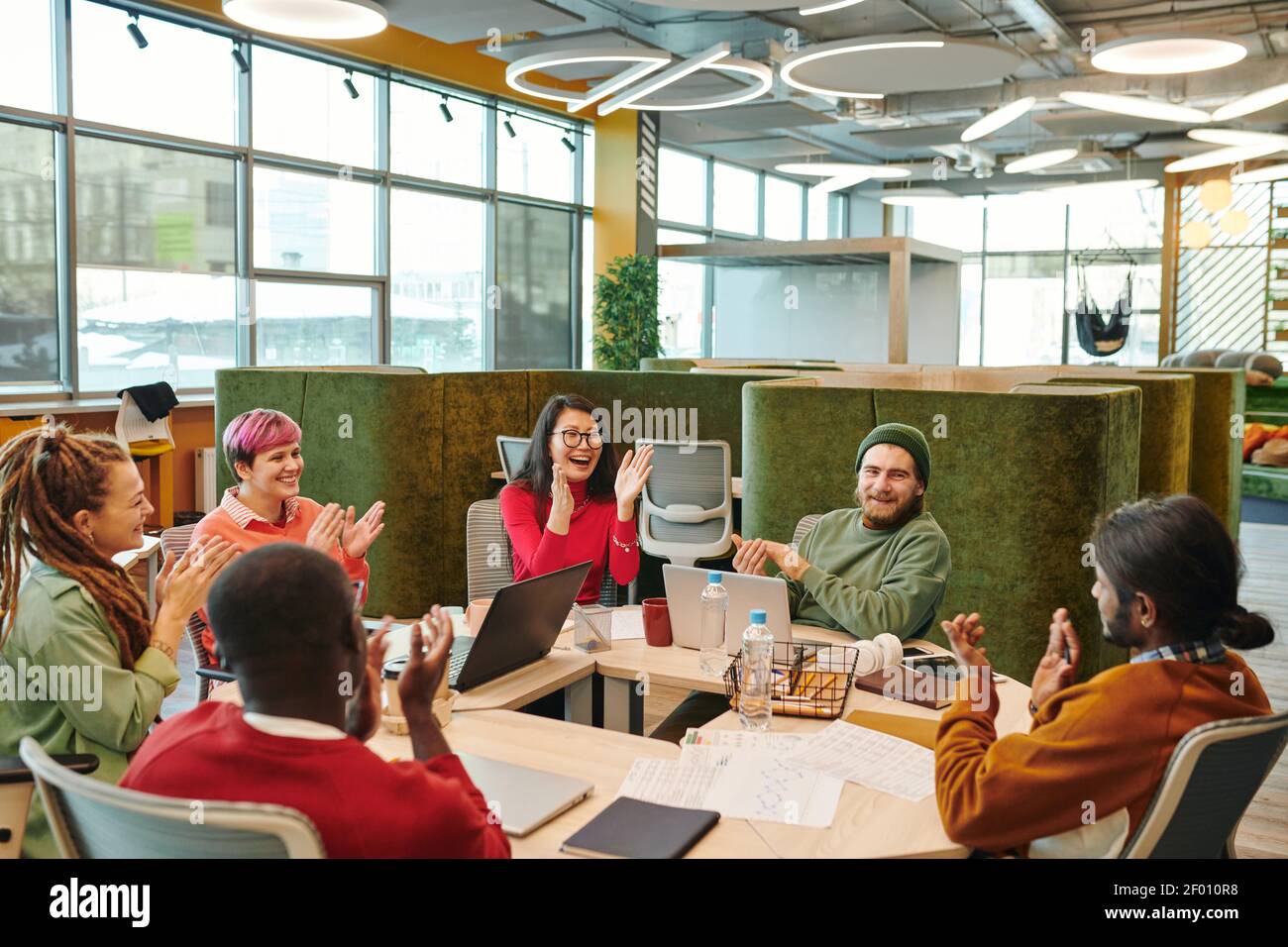 Their Making Medium group of cheerful young intercultural clapping hands while ...
