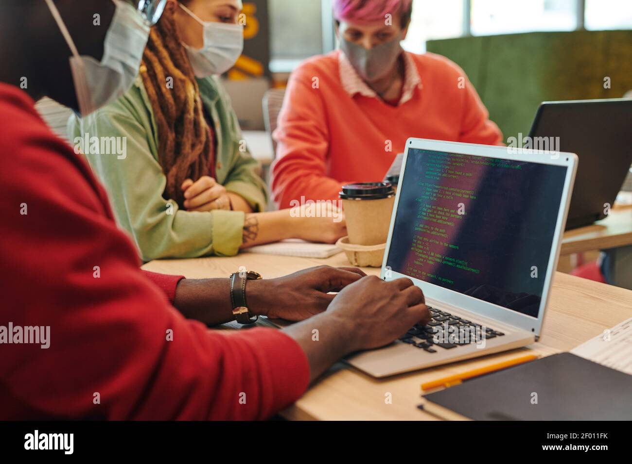 Hands of young it engineer of African ethnicity touching keys of laptop keypad while working over new program or software by workplace Stock Photo