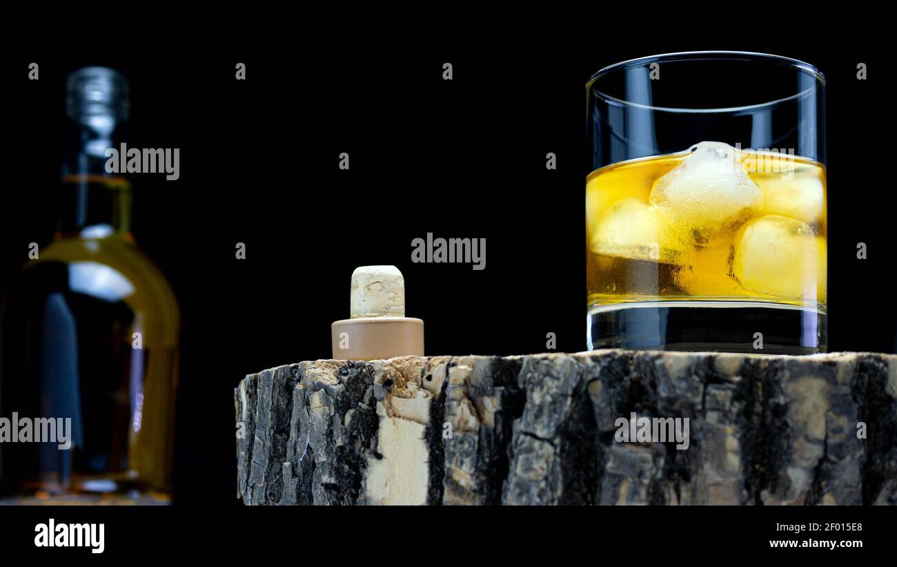 Whiskey with ice on a rustic style on a black background. Scotch