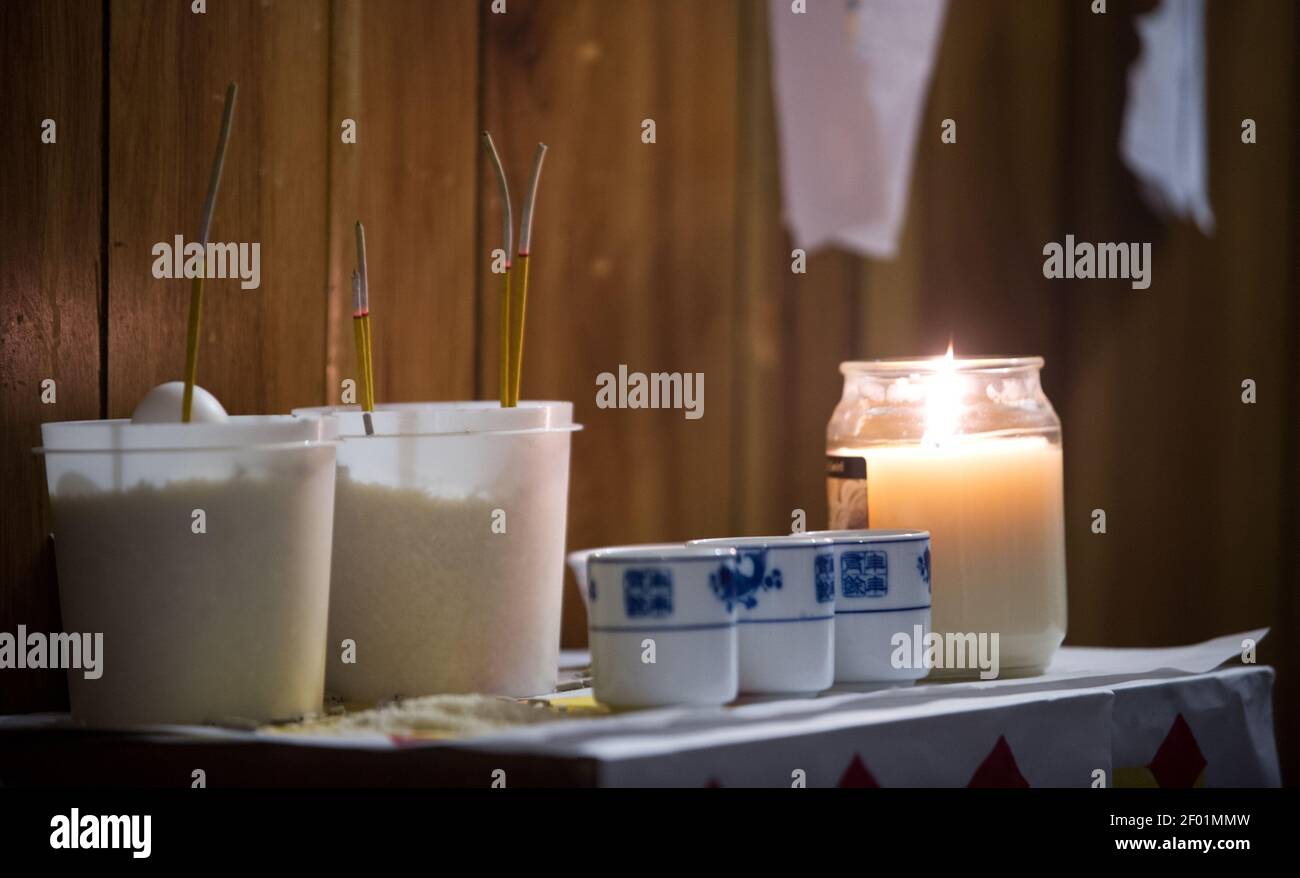On the family altar, buckets of rice hold incense and an egg, a symbol ...