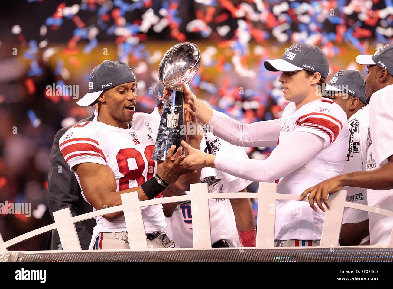 Wide receiver Victor Cruz (80) of the New York Giants and kicker Lawrence  Tynes (9) of the New York Giants hold the championship trophy at the end of  Super Bowl XLVI on