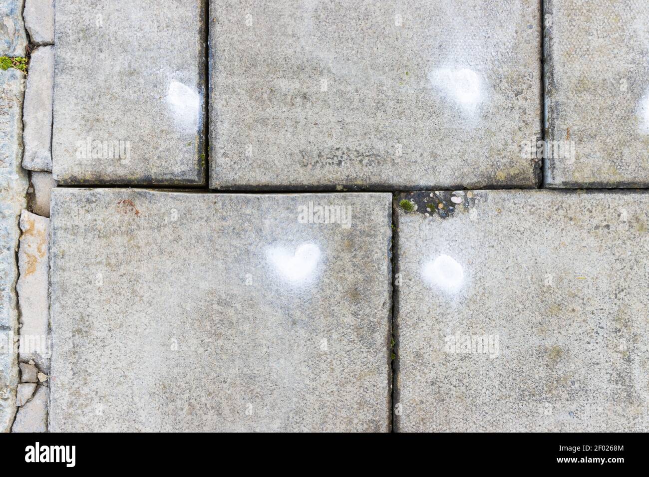 A grey concrete pavement slab with a white spray paint on it, with