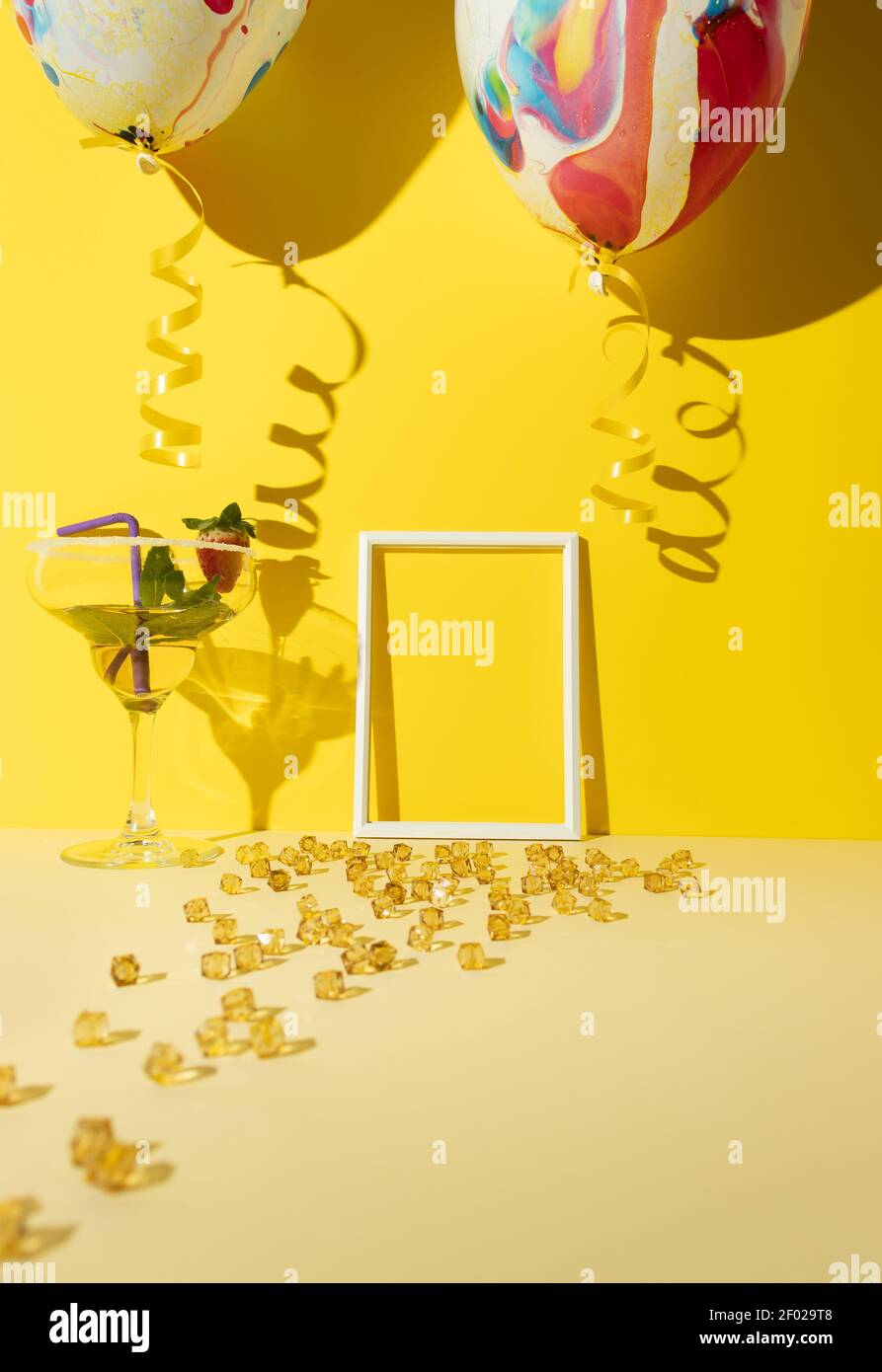 Coctail in a tall glas with sugar, mint leaves, strawberry and straw on a beige surface with golden beads against a yellow background with a colorful Stock Photo