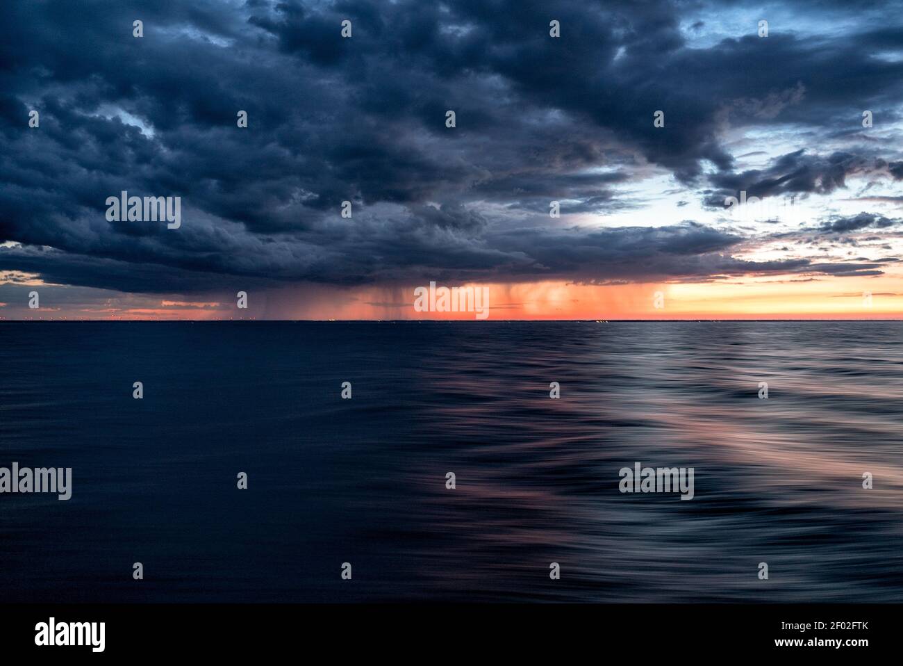 The dark clouds of the sunset sky over the dark water of the ocean ...