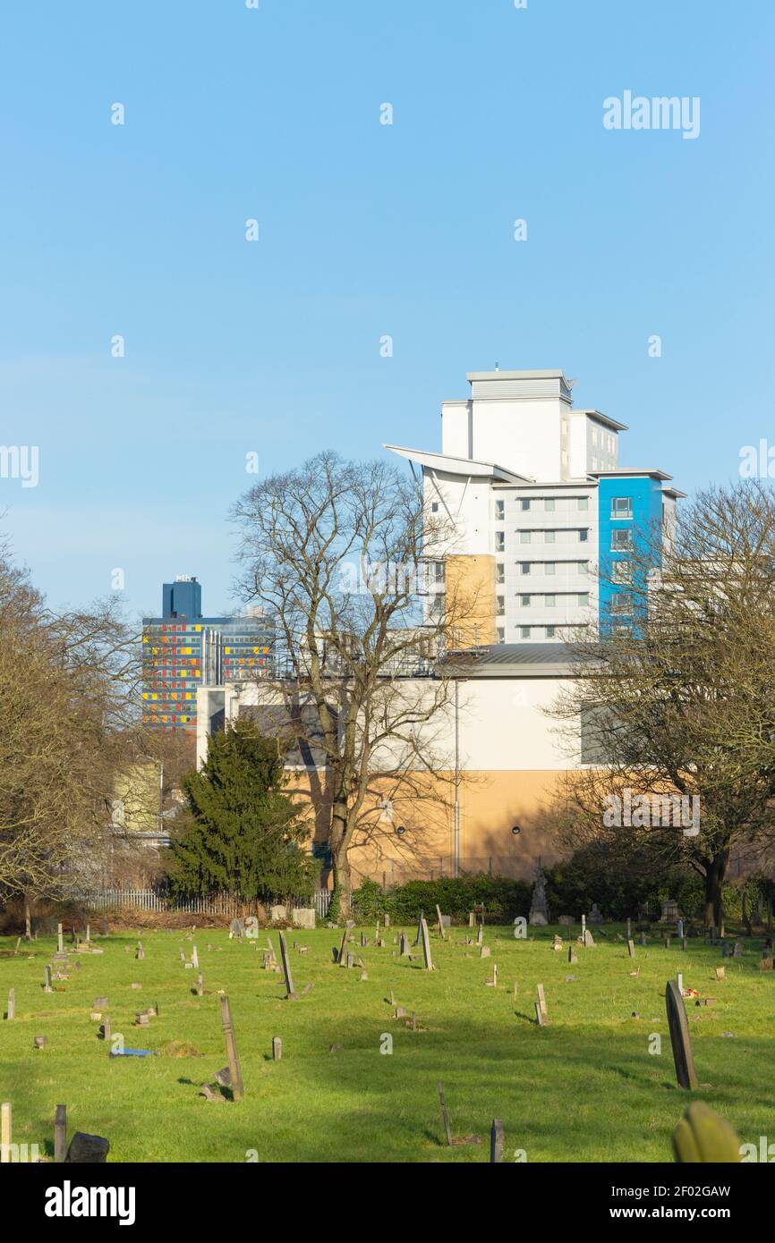 Shows grave stones side-on in the foreground, then in the background St. George’s Tower and The University of Leicester: Opal Court. Stock Photo
