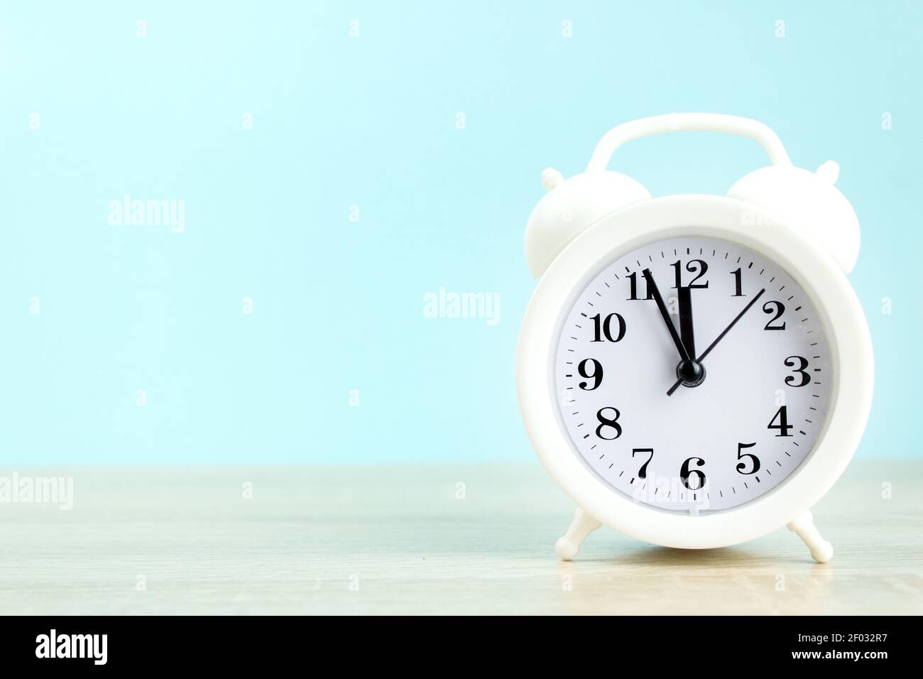 White alarm clock on wood table with blue background Stock Photo - Alamy
