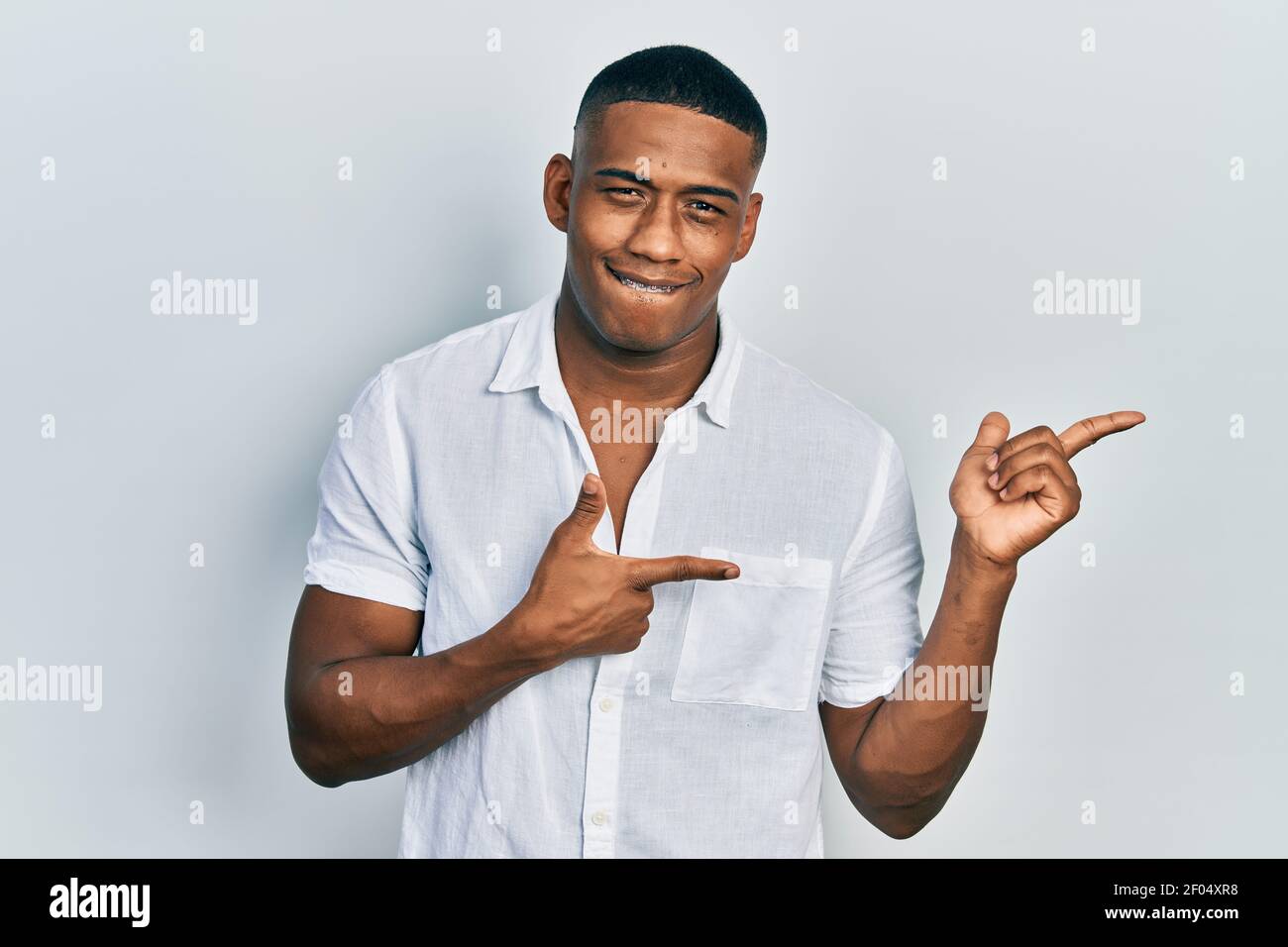Young black man wearing casual white shirt smiling and looking at the ...