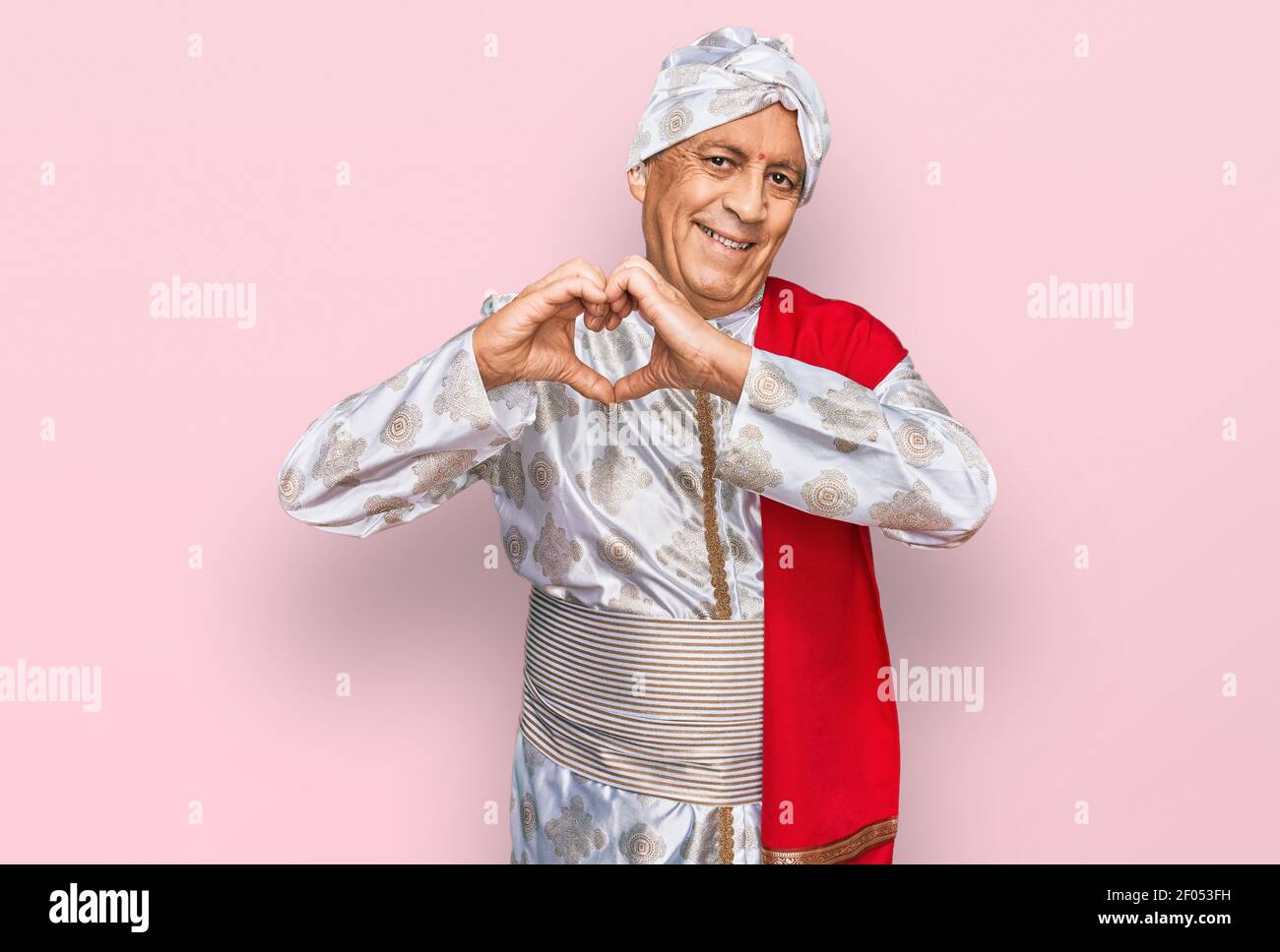 Senior hispanic man wearing tradition sherwani saree clothes smiling in love doing heart symbol shape with hands. romantic concept. Stock Photo