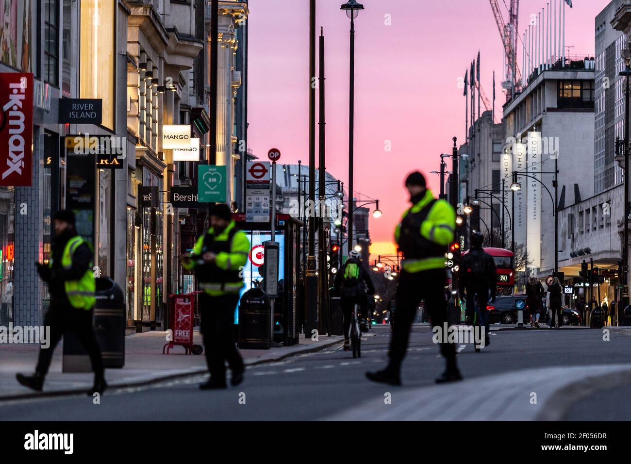 London, UK, March 6, 2021. Commuters cross Oxford Street as the sun sets over largely empty street during an ongoing third Coronavirus lockdown. Oxford Street is usually busy with crowds of shoppers. The Prime Minister Boris Johnson has set a road map on easing the restrictions. Credit: Dominika Zarzycka/Alamy Live News Stock Photo