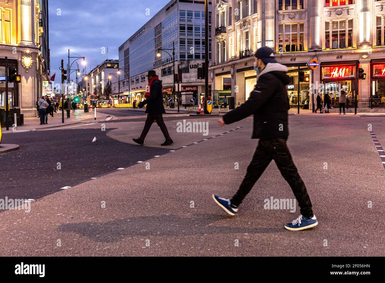 London, UK, March 6, 2021. Commuters cross Oxford Circus as the sun sets over largely empty streets during an ongoing third Coronavirus lockdown. Oxford Street is usually busy with crowds of shoppers. The Prime Minister Boris Johnson has set a road map on easing the restrictions. Credit: Dominika Zarzycka/Alamy Live News Stock Photo