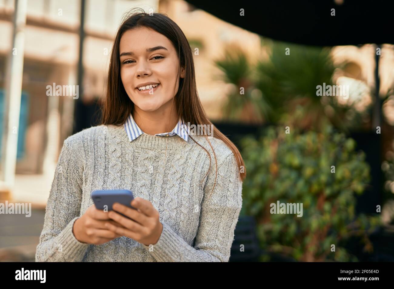 Young hispanic girl smiling happy using smartphone at the city Stock ...