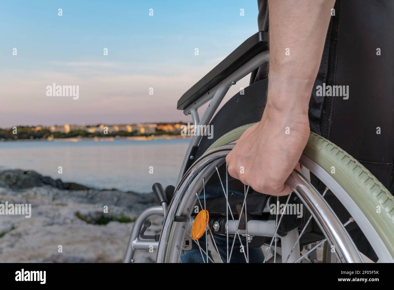 Disabled man sitting on wheelchair near sea at sunset Stock Photo - Alamy