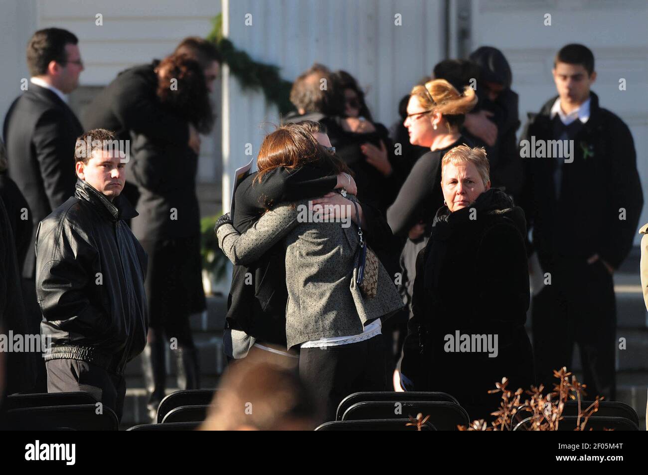 Mourners console each other after a funeral service for teacher