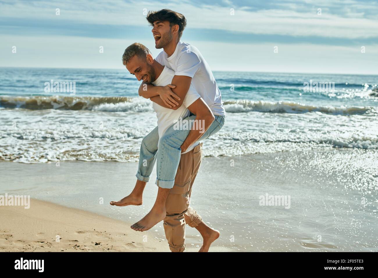Lovely gay couple on piggyback ride at the beach Stock Photo - Alamy