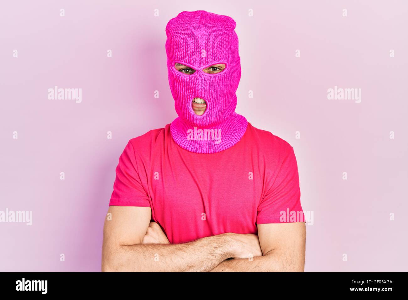 Young hispanic man with modern dyed hair wearing pink balaclava mask face happy face smiling with crossed arms looking at the camera. positive person. Stock Photo