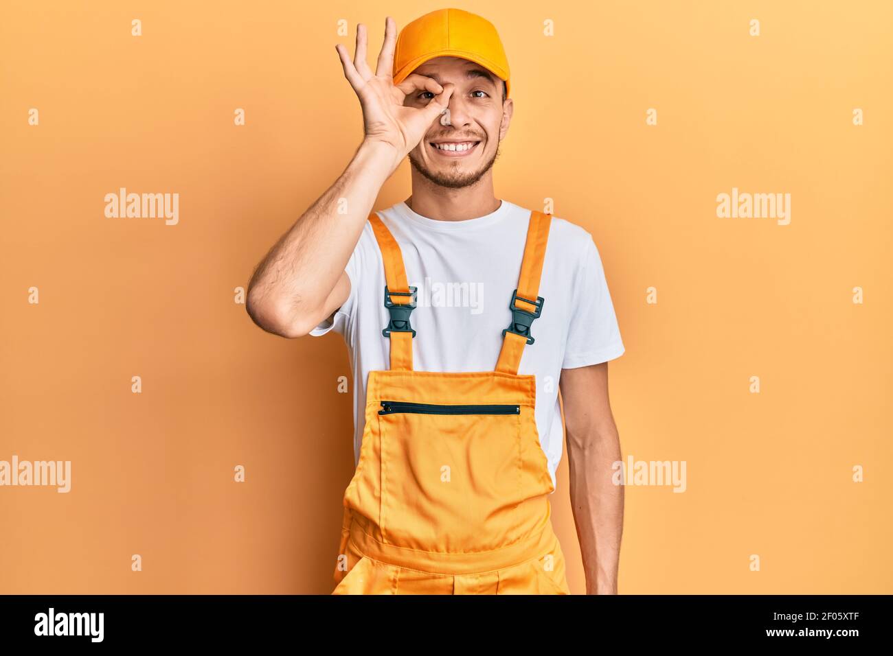 Hispanic young man wearing handyman uniform doing ok gesture with hand ...