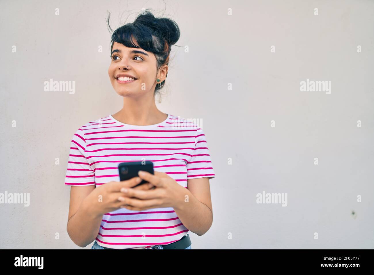 Young hispanic girl smiling happy using smartphone at the city Stock ...