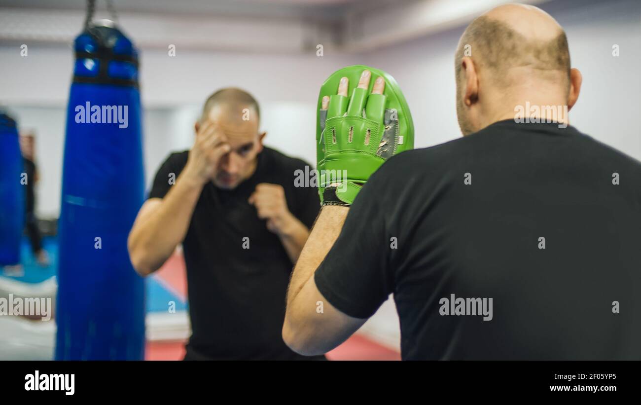 Instructor holds focus mitts. Boxing kick training and demonstration ...