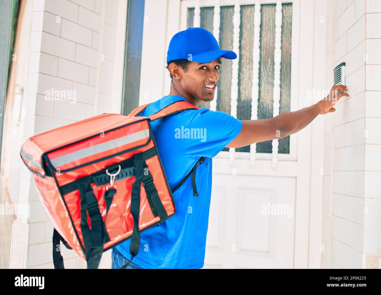 African delivery man wearing courier uniform outdoors knocking on the ...