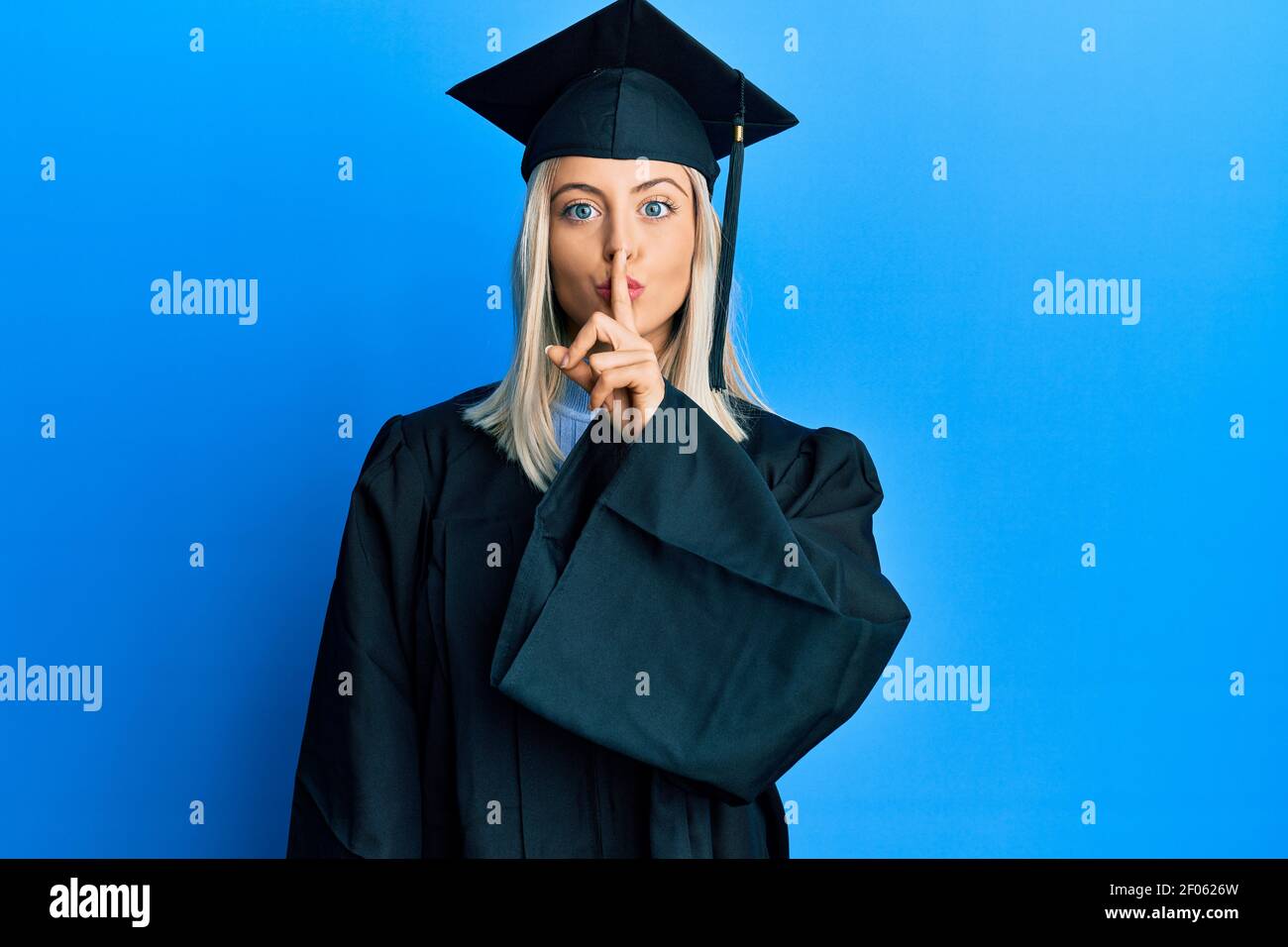 Beautiful blonde woman wearing graduation cap and ceremony robe asking ...