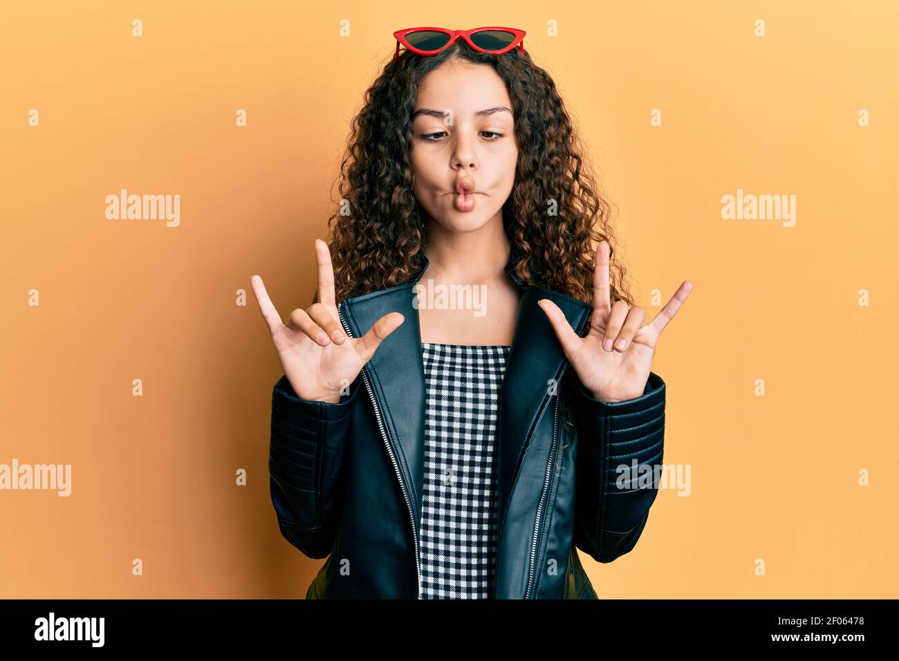 Squinting Rocks Teenager hispanic girl doing rock gesture making fish face with mouth ...