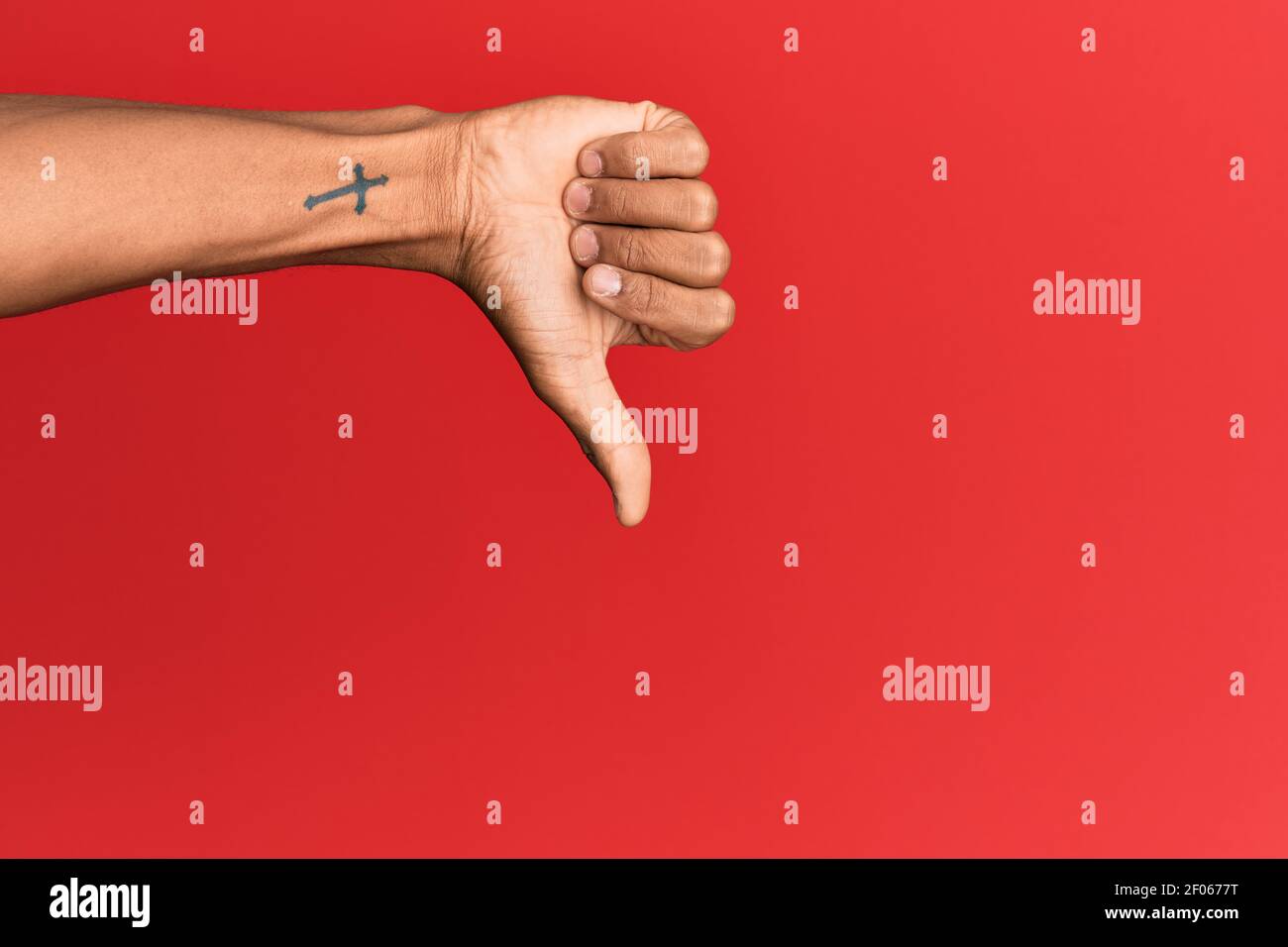 Hand of hispanic man over red isolated background doing thumbs down ...
