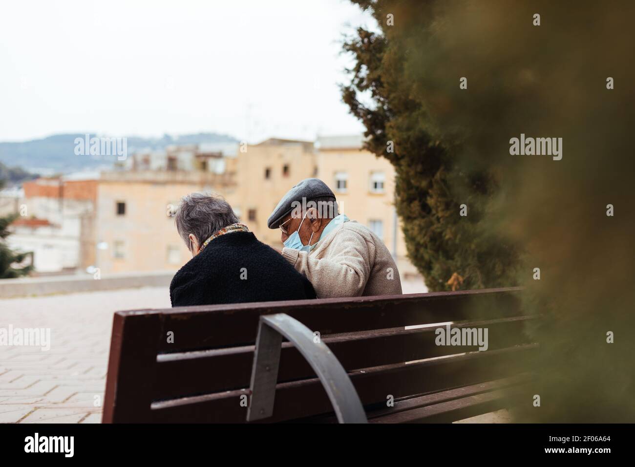 Back view of an unrecognizable elderly couple sitting on a park bench ...
