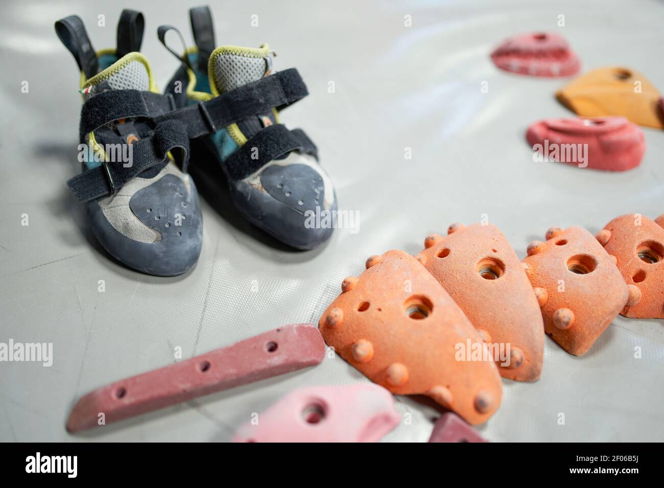 Various climbing holds and professional shoes for albinism on mat in bouldering center Stock Photo