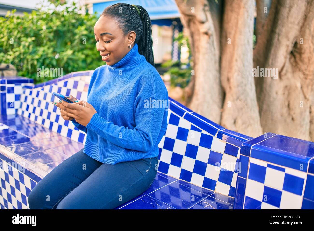 Young african american woman smiling happy using smartphone sitting on ...