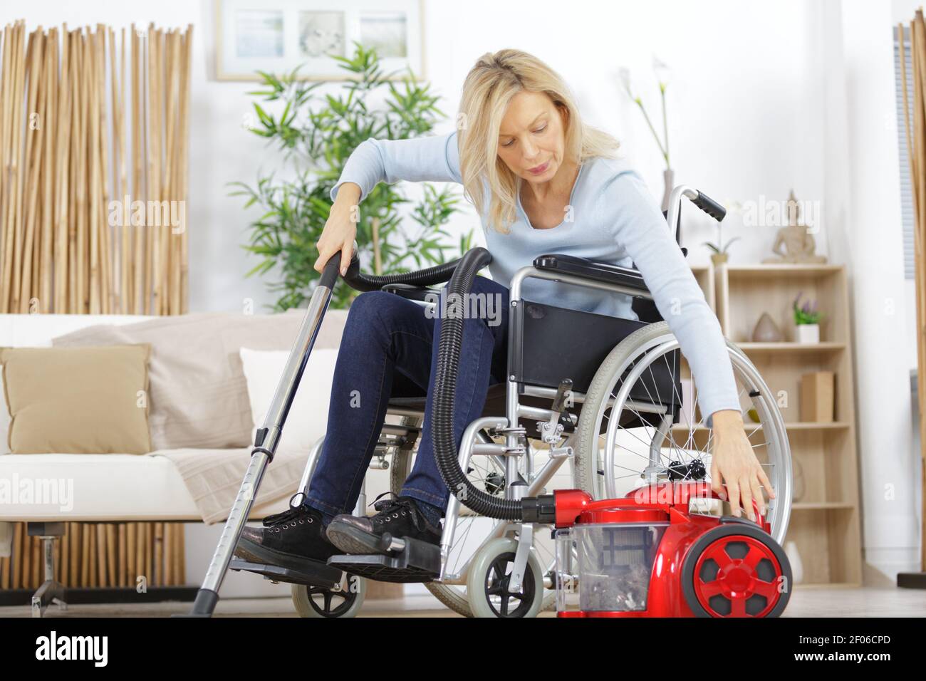 woman on wheelchair using vacuum cleaner Stock Photo Alamy