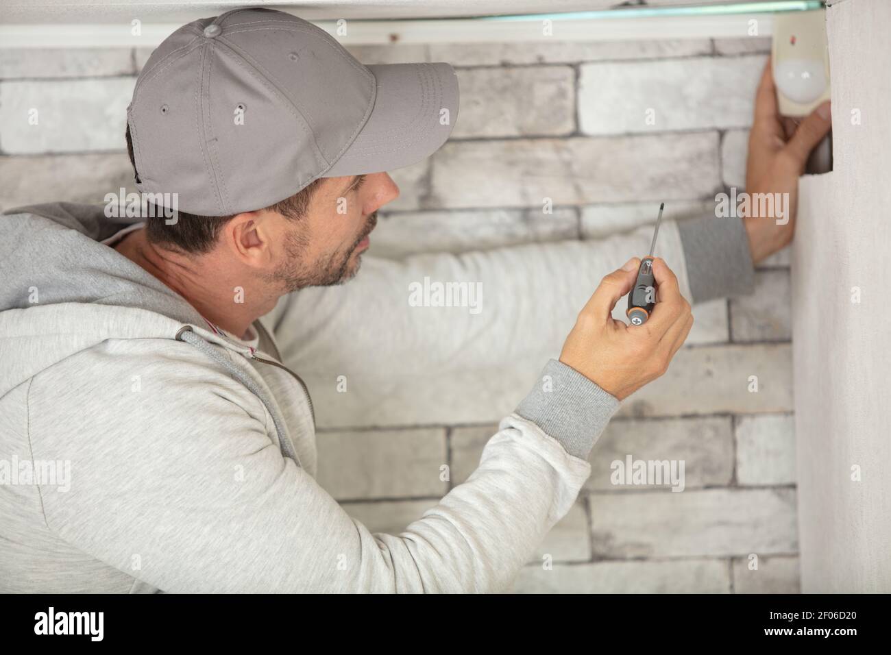 repairman fixing wall with screwdriver Stock Photo Alamy