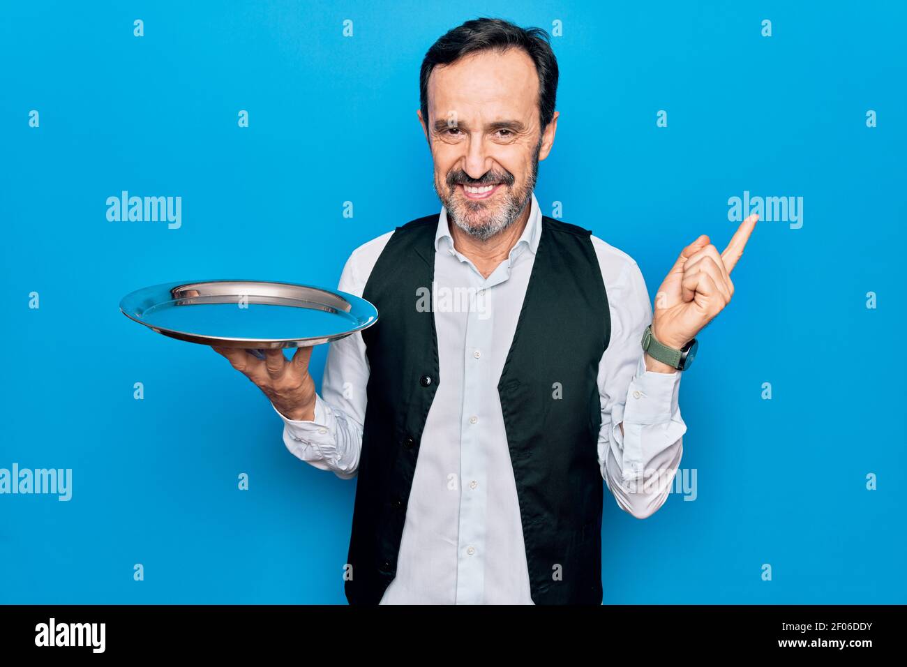 Waitressing Man Middle age handsome waitress man holding tray standing over isolated ...