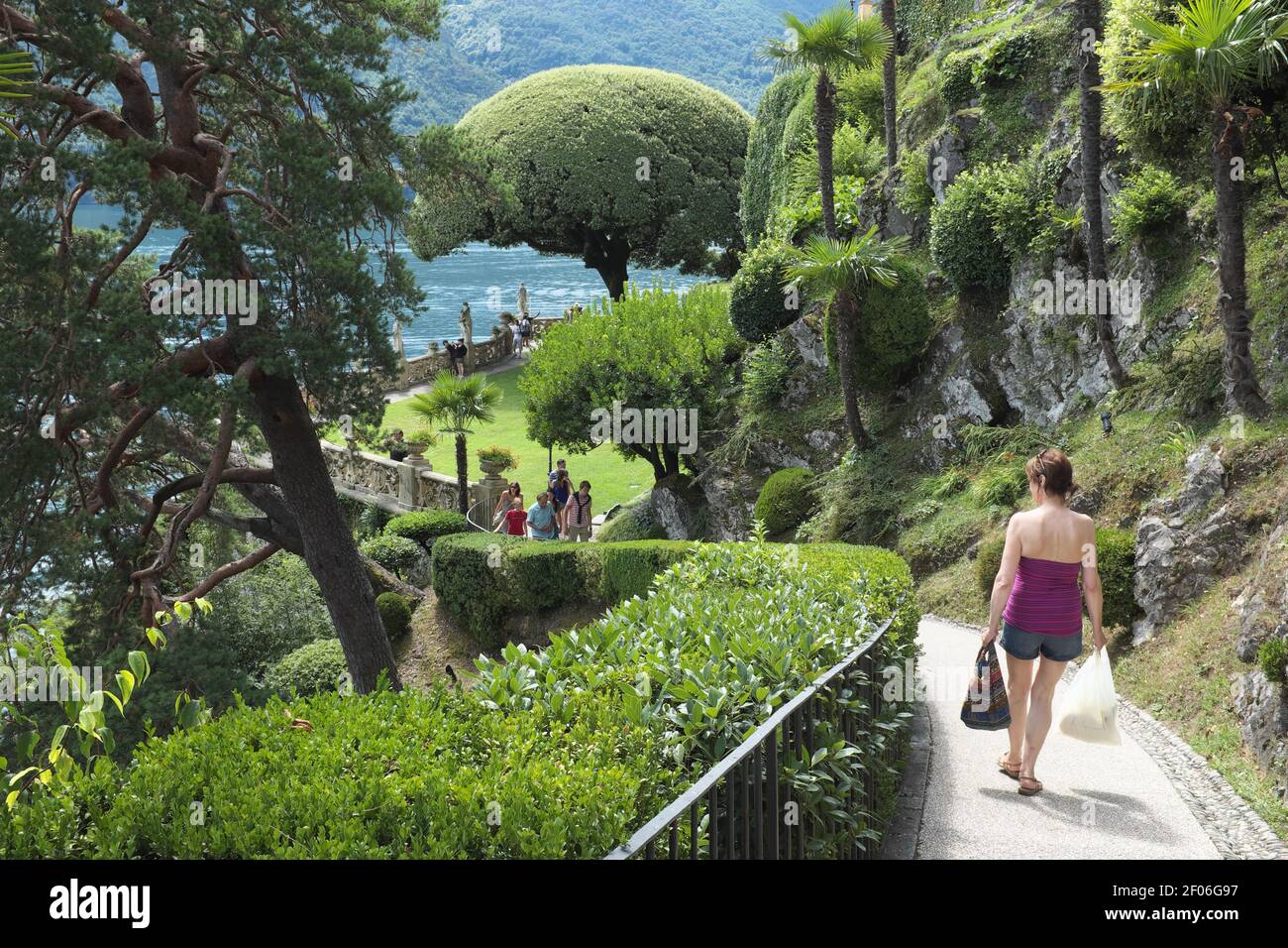 Young Woman Walking Down A Path Into The Gardens Of The Villa del Balbianello In Lenno Lombardy Lake Como Italy Stock Photo