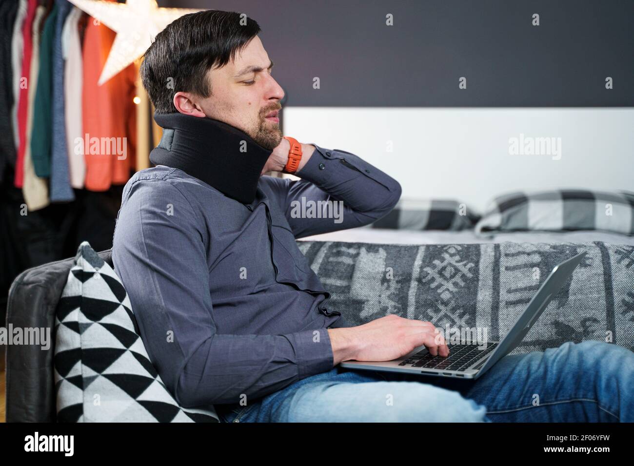 Tired strained man suffering from neck pain while working at computer