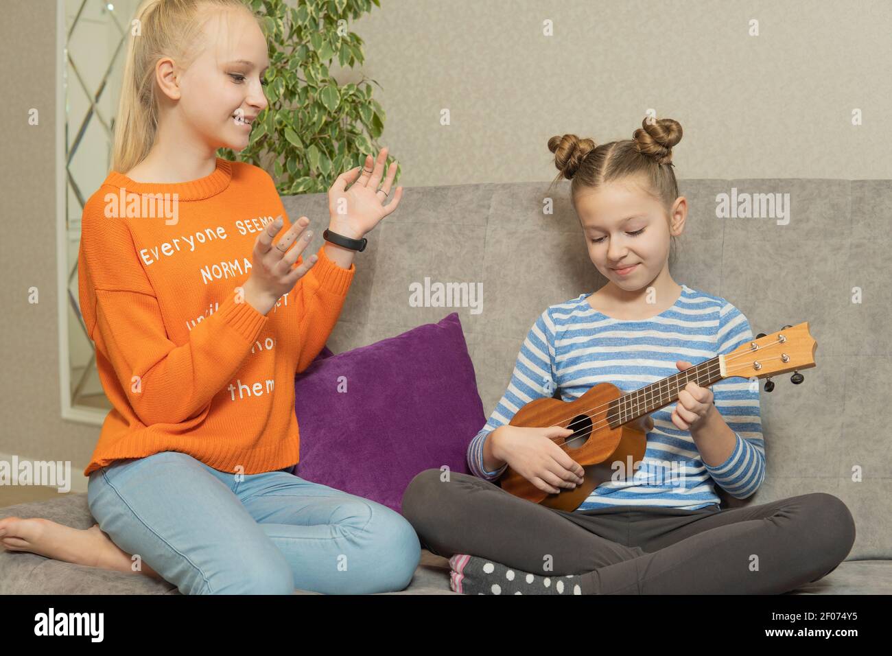 two teenage girls sit on the couch and play the Hawaiian ukulele Stock  Photo - Alamy