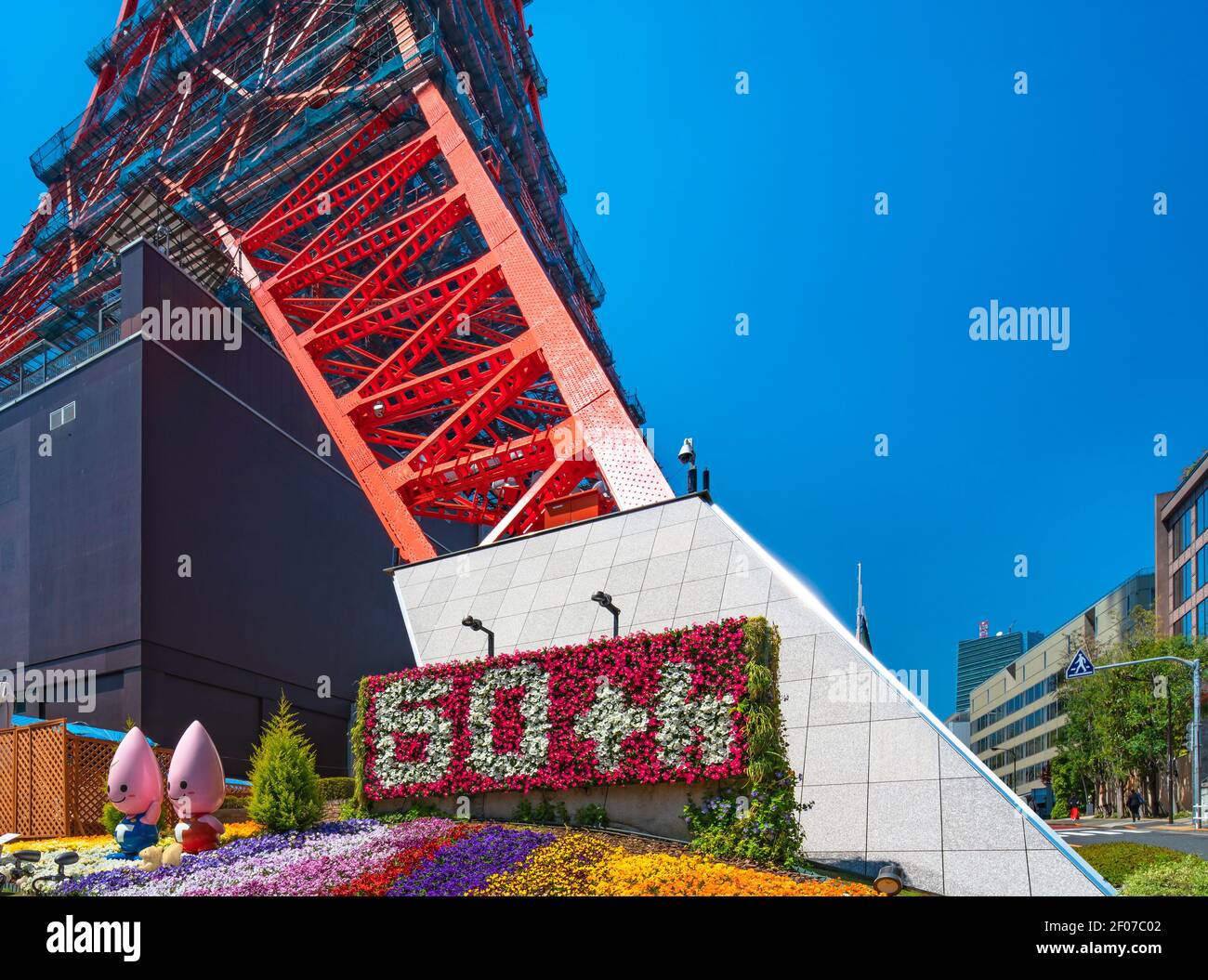 tokyo, japan - march 02 2021: Close up on the foot of the sightseeing landmark Tokyo tower adorned with colorful flowers and Noppon Brothers mascots f Stock Photo