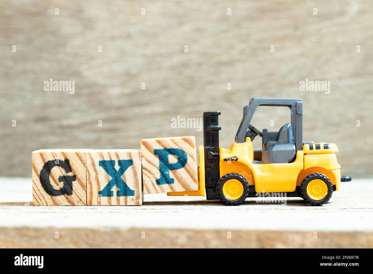 Toy forklift hold letter block P to complete word GXP on wood background Stock Photo