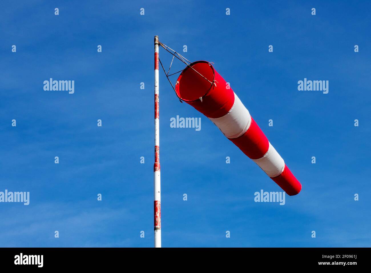 Wind sock red white striped bag on pole against blue sky Stock Photo