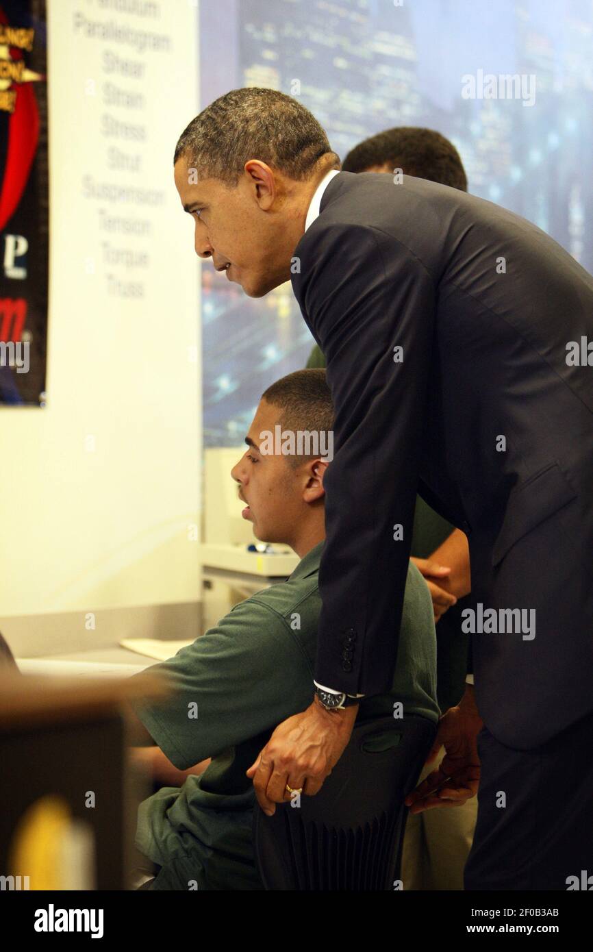 President Barack Obama leans over a student in a science class to see ...