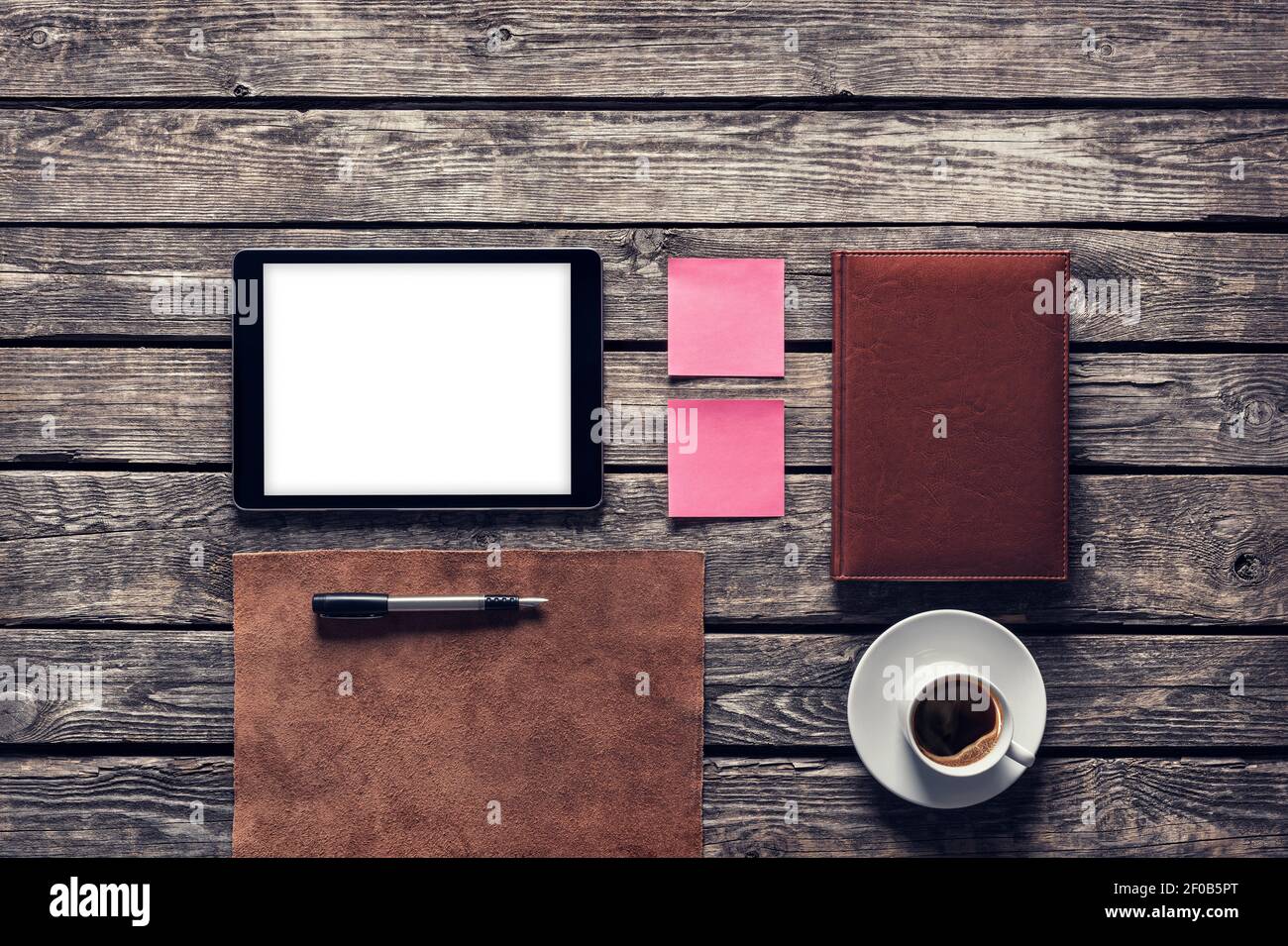 Tablet computer with notes and coffee cup on wooden desk. Clipping path. Stock Photo