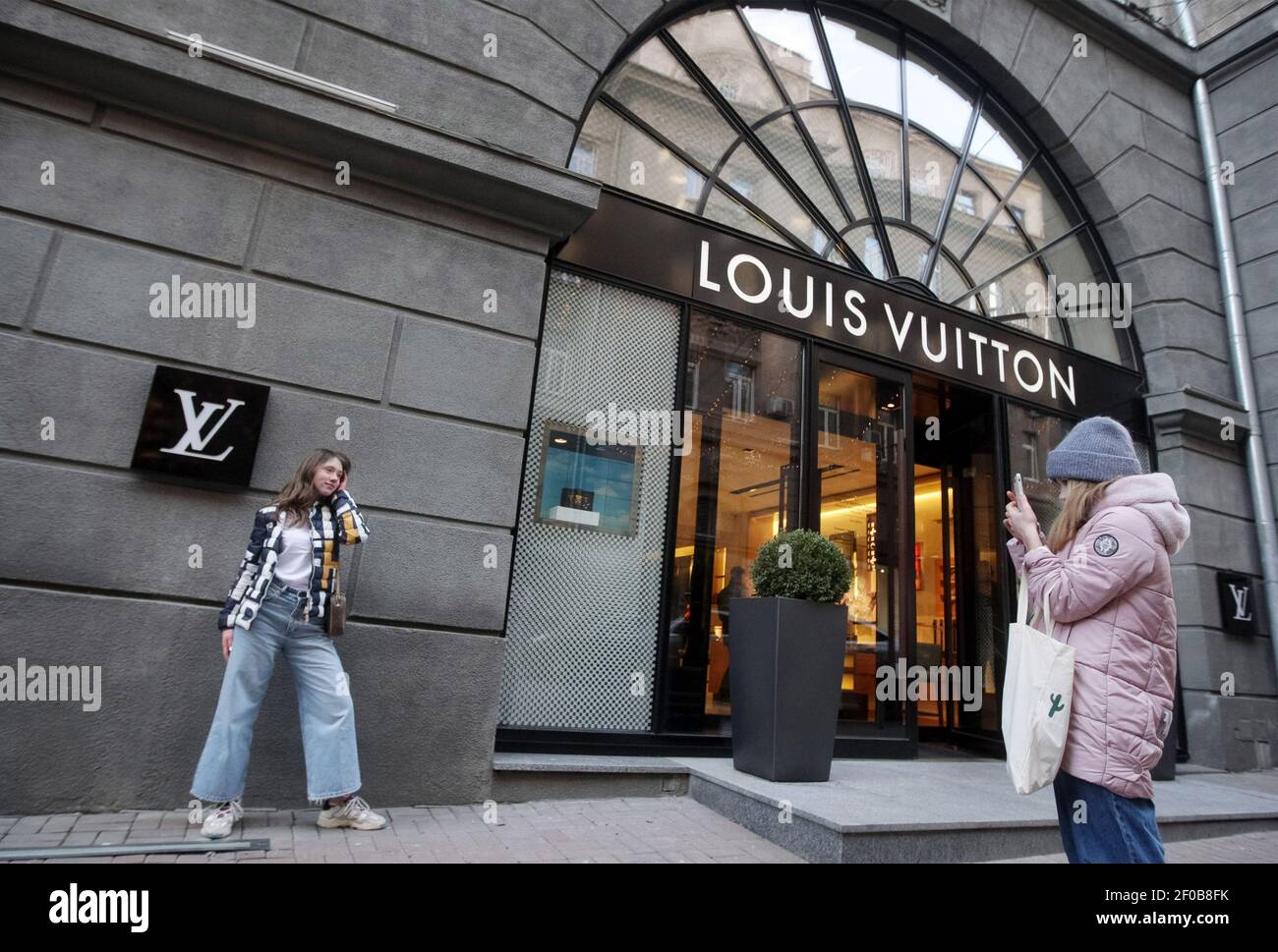 Kiev, Ukraine. 06th Mar, 2021. A girl poses for a photo next to Vuitton logo or shortened to LV of a French fashion house and luxury goods company brand in