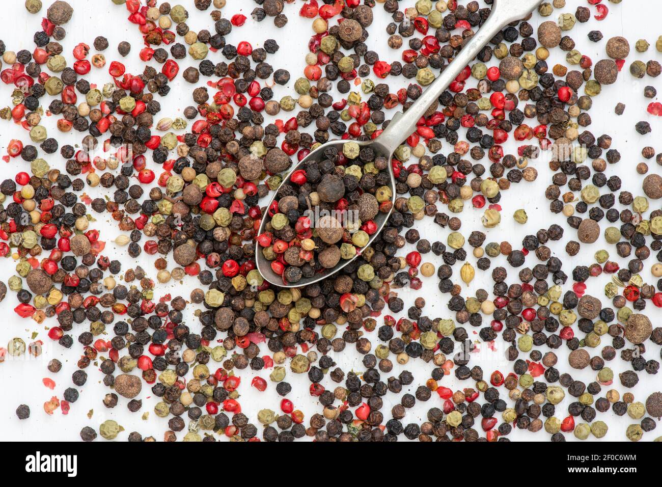 Mixed peppercorns and spoon on a white background Stock Photo