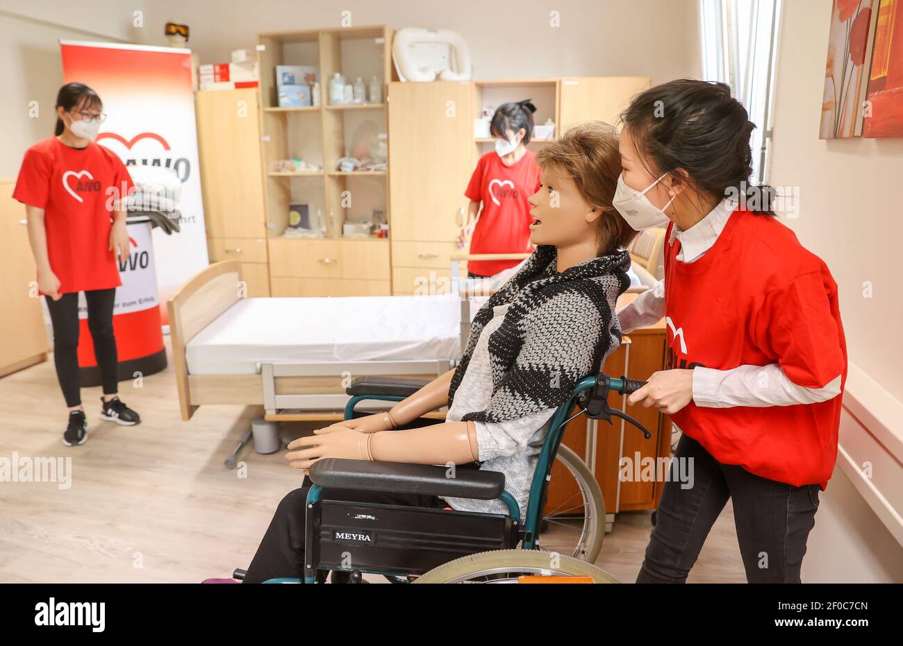 24 February 2021, Saxony, Auerbach (vogtland): The Vietnamese Tuoi Phung (l-r), Oanh Nguyen and Nhung Bui take care of training dummy Elvira in the training room of the Arbeiterwohlfahrt Vogtland (AWO). The three young women came to Vogtland from their home country Vietnam in 2017 for training. This is now finished - since the beginning of March, they have been working for the AWO as skilled nursing staff. These are in short supply and the need is growing steadily due to the aging population. Four years ago, they were the first, now almost half of the trainees in the field of care at the socia Stock Photo