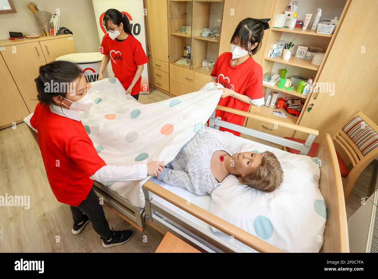 24 February 2021, Saxony, Auerbach (vogtland): The Vietnamese women Nhung Bui (l-r), Tuoi Phung and Oanh Nguyen take care of training dummy Elvira in the training room of the Arbeiterwohlfahrt Vogtland (AWO). The three young women came to Vogtland from their home country Vietnam in 2017 for training. This is now finished - since the beginning of March, they have been working for the AWO as skilled nursing staff. These are in short supply and the need is growing steadily due to the aging population. Four years ago, they were the first, now almost half of the trainees in the field of care at the Stock Photo