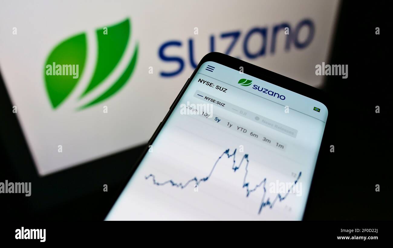 Smartphone with website and stock chart of Brazilian pulp and paper manufacturer Suzano SA on screen with logo. Focus on top-center of phone display. Stock Photo